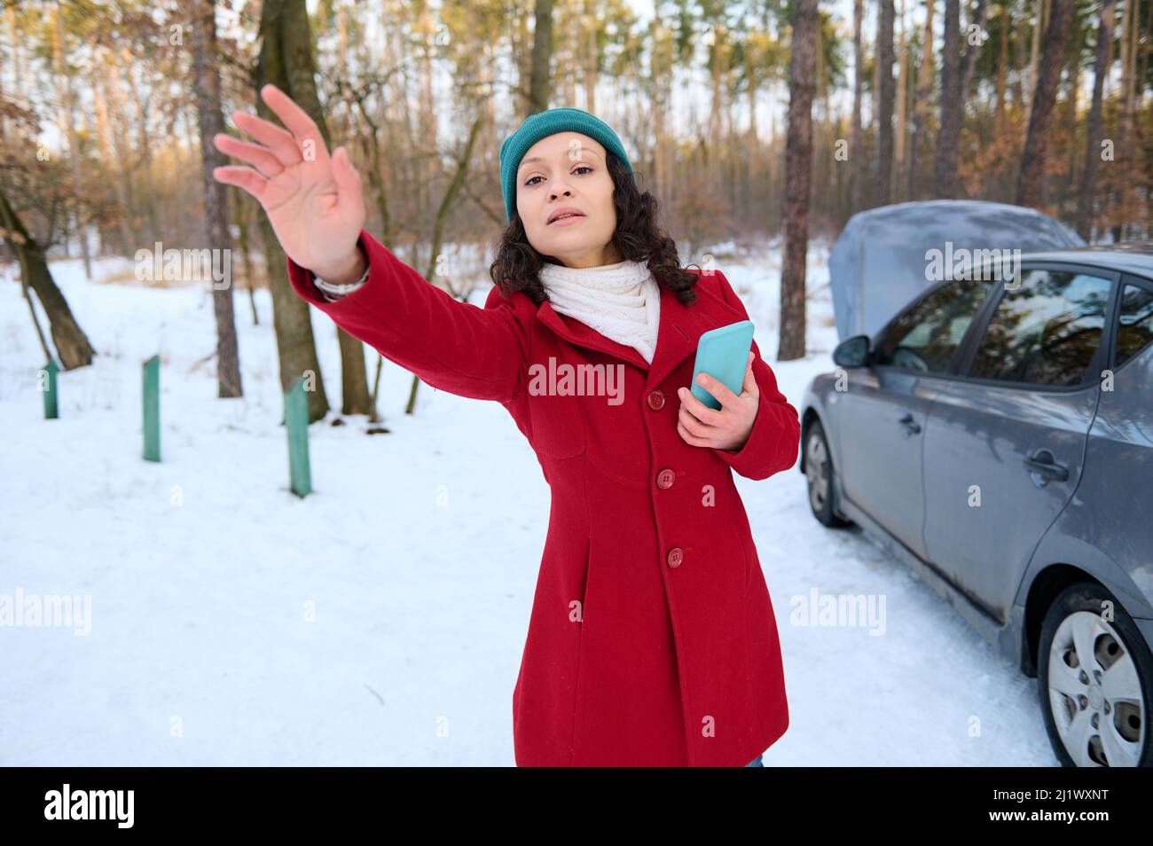 Frustrata disperata giovane donna caucasica, conducente con telefono cellulare, cercando di trovare aiuto durante un guasto auto. Dispositivo di frenatura automatico. Breakdow auto Foto Stock