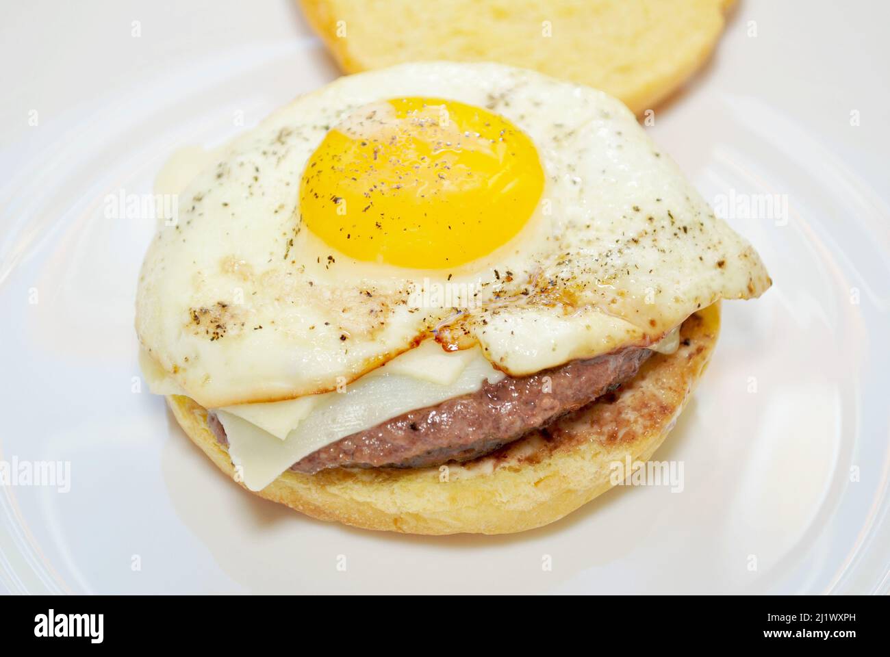 Uovo fritto in cima a un raro Cheeseburger Foto Stock