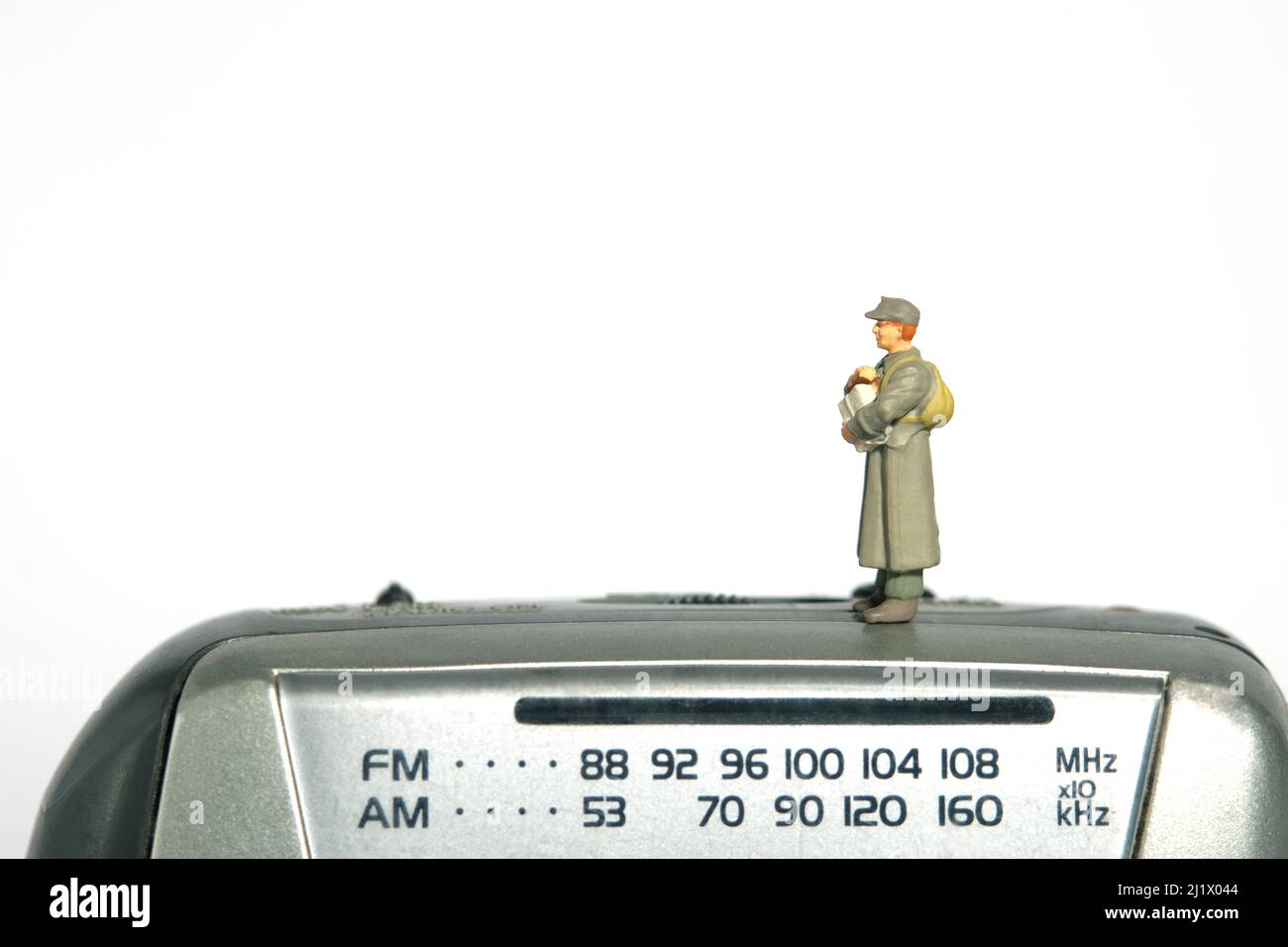 Fotografia di personaggi giocattolo in miniatura. Un ufficiale di posta militare che tiene la busta del bollettino in piedi sopra il dispositivo fm della radio. Isolato su backgrou bianco Foto Stock