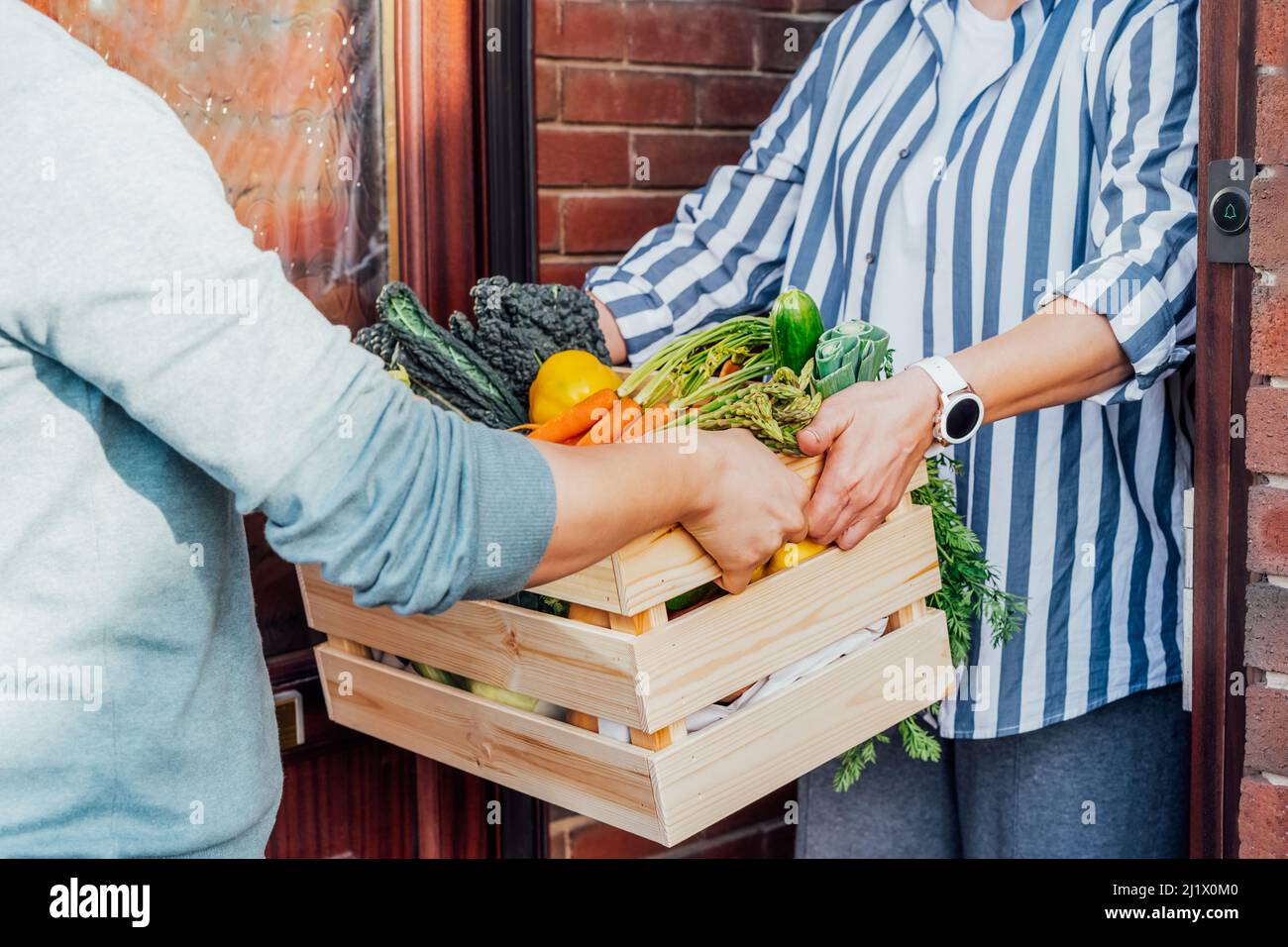 Consegna di cibo fresco in casa. Donna che prende scatola di legno con verdure e frutta. Sostenere la produzione alimentare agricola locale . Nuovo inizio di una vita sana, weig Foto Stock