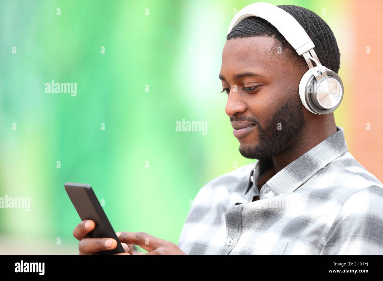 Uomo con pelle nera che ascolta musica controllo cellulare Foto Stock