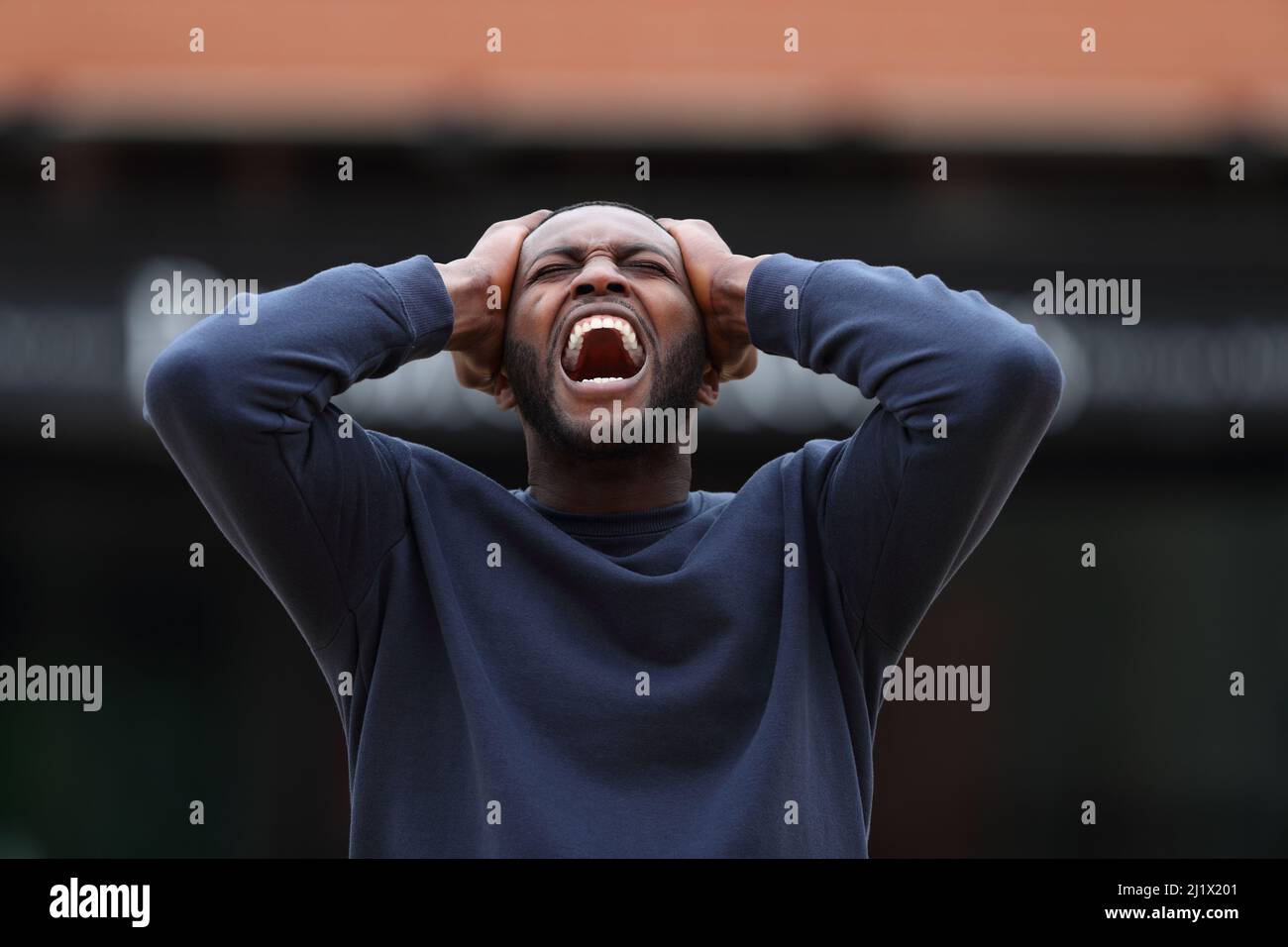 Vista frontale ritratto di un uomo stressato con pelle nera urlando in strada Foto Stock