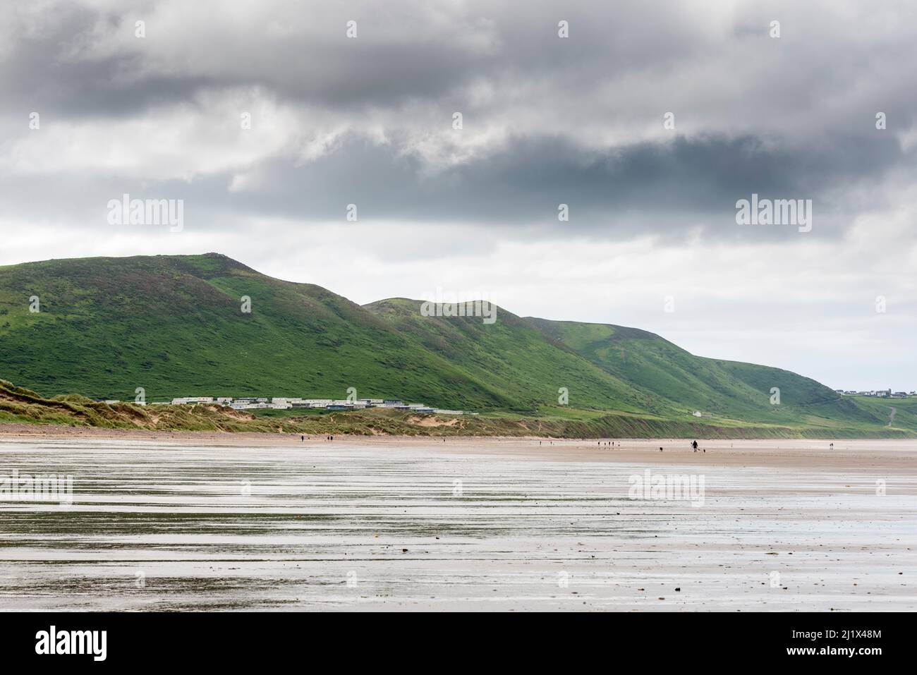 Una vista estesa lungo l'enorme spiaggia sabbiosa di Rhossili Bay con la bassa marea. In lontananza è Hillend campeggio ai piedi di Rhossili giù . Foto Stock