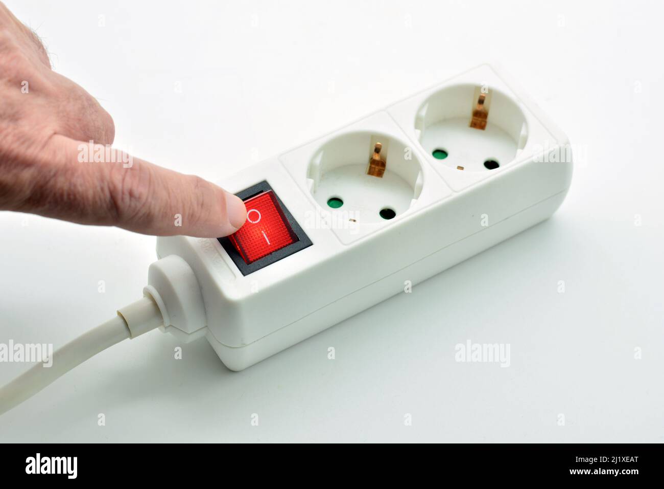 Dedo apagando un interruptor de una regleta eléctrica endido, aislado sobre fondo blanco Foto Stock