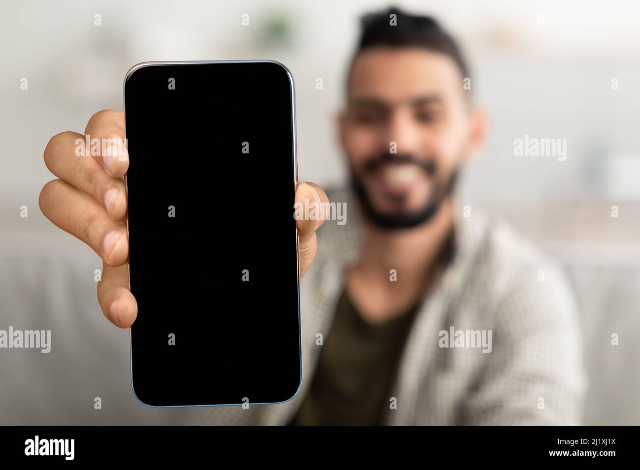 Ragazzo arabo che mostra smartphone con grande schermo vuoto, giovane che  consiglia nuova app mobile o sito web, mockup Foto stock - Alamy