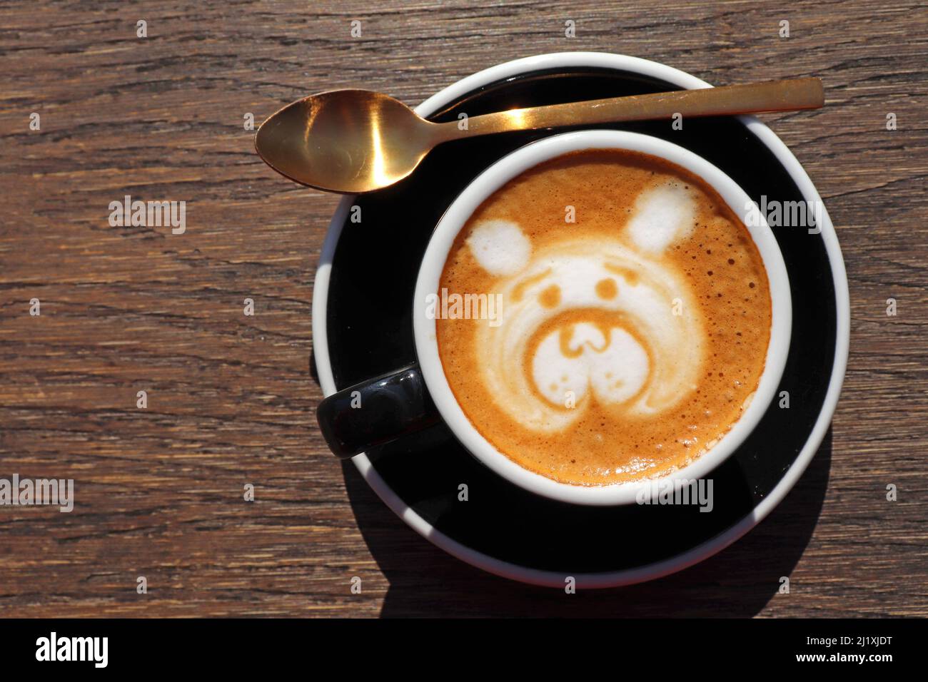 Latte art, disegno del volto dell’orso, caffè art fatto da barista con cucchiaio d’oro su tavola di legno, vista dall’alto o dall’alto. Spazio di copia f Foto Stock