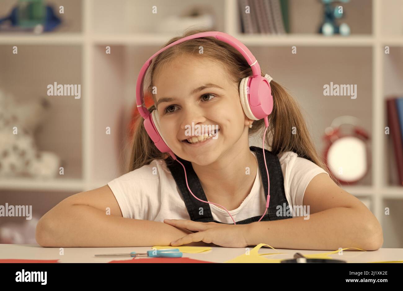 happy kid ascolta la musica in cuffia durante la lezione scolastica in classe, formazione online Foto Stock