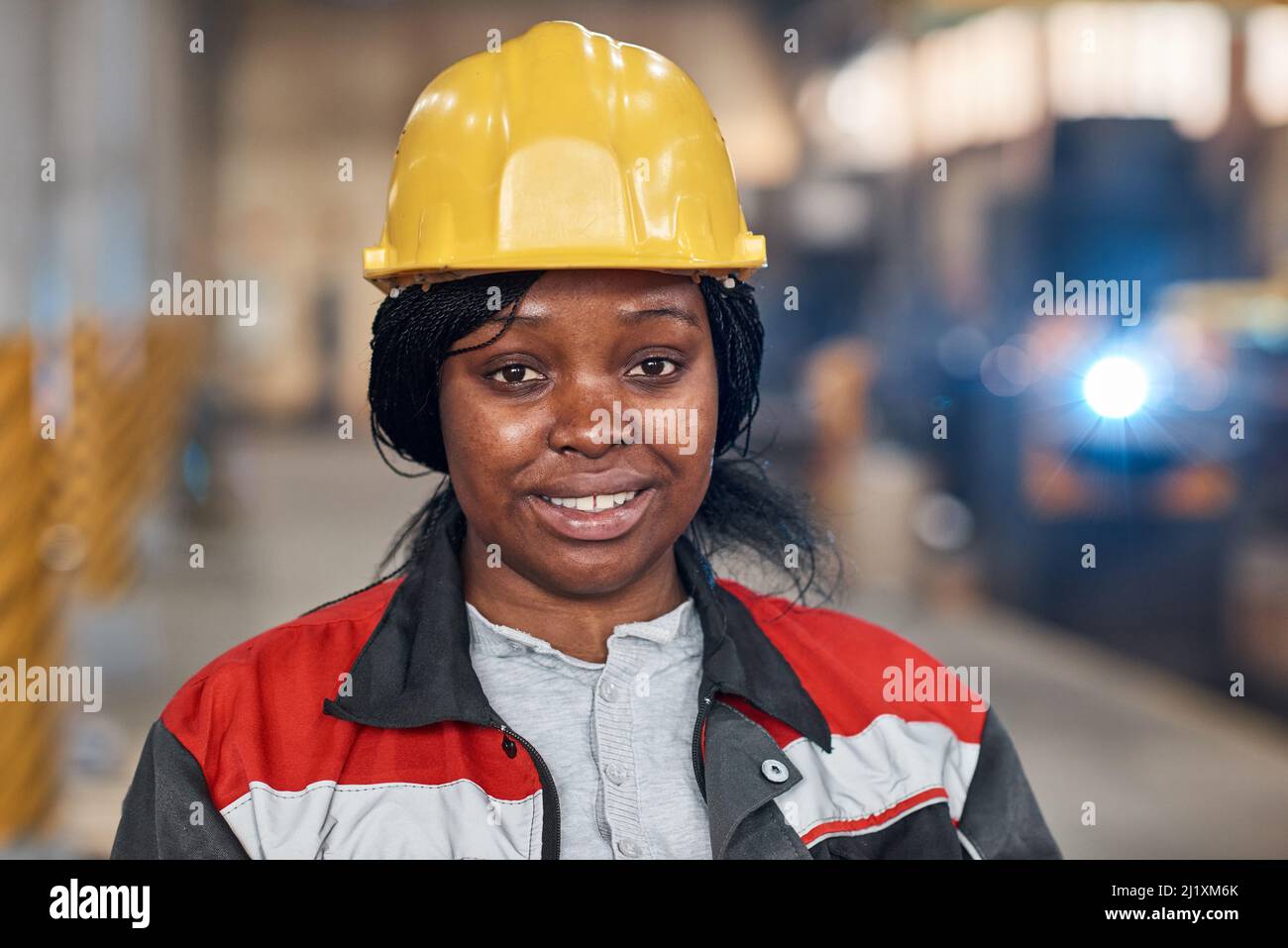 Ritratto di giovane donna africana in casco di lavoro e uniforme sorridente a macchina fotografica di lavoro in fabbrica Foto Stock