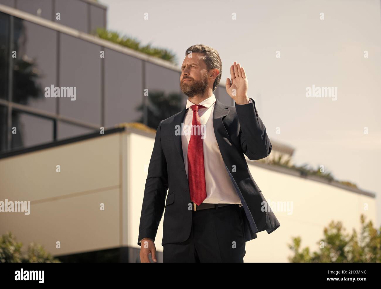 bell'uomo uomo d'affari in tuta e cravatta rossa all'aperto mostra ciao o stop gesto, gesturing Foto Stock
