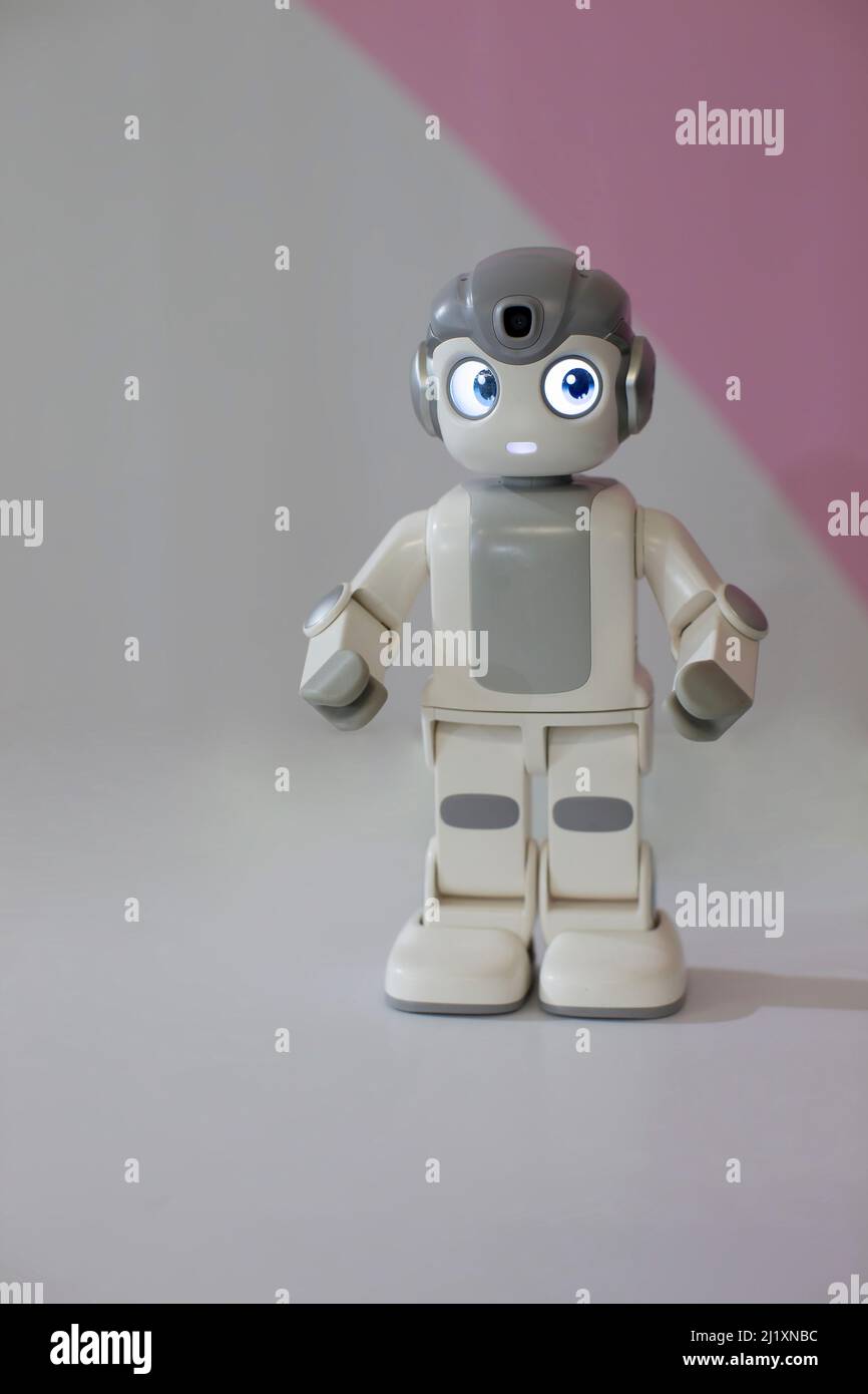 Figura di un piccolo robot su sfondo grigio. Foto Stock