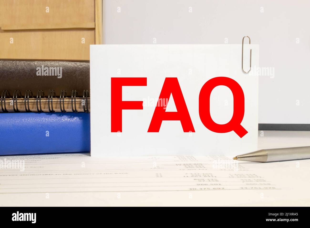 Notebook, penna e una tazza di caffè sul tavolo di legno. Notebook FAQ scritta - Frequenza Domanda il concetto di business. Foto Stock