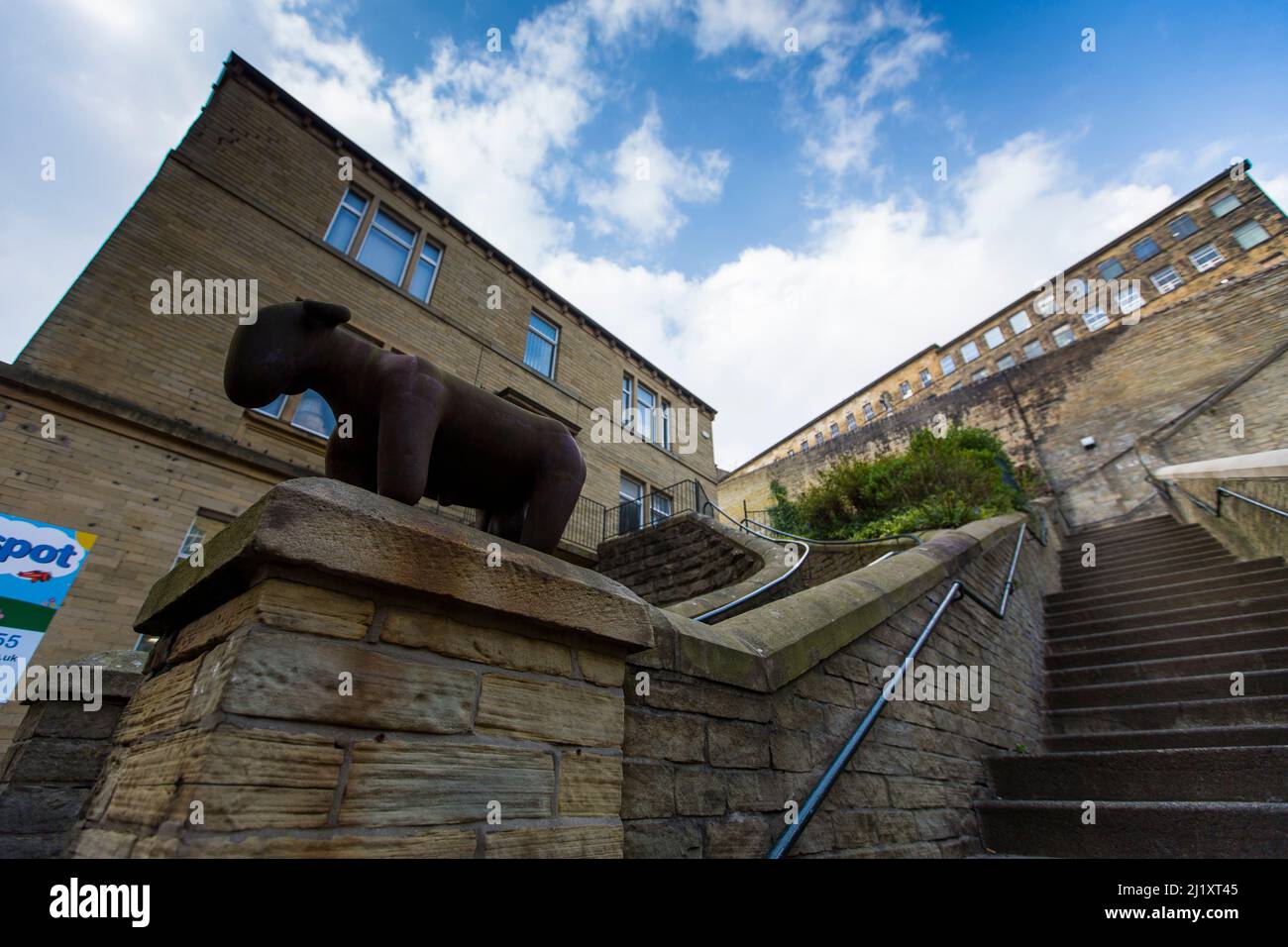 Dean Clough di Halifax, Calderdale, West Yorkshire, Inghilterra, è un gruppo di grandi fabbriche costruite nel 1840s–60s per i tappeti Crossley, diventando una delle più grandi fabbriche di tappeti del mondo (mezzo miglio di lunghezza con 1.250.000 piedi quadrati (116.000 m2) di spazio pavimento). Dopo anni di declino della produzione, la società si è chiusa nel 1983, quando è stata acquistata da un consorzio guidato da Sir Ernest Hall che ha sviluppato il sito classificato di grado II per vari usi commerciali e culturali. Ora è visto come un esempio principale di rigenerazione urbana riuscita.Dean Clough è situato sul lato nord di Halifax vicino al V Foto Stock