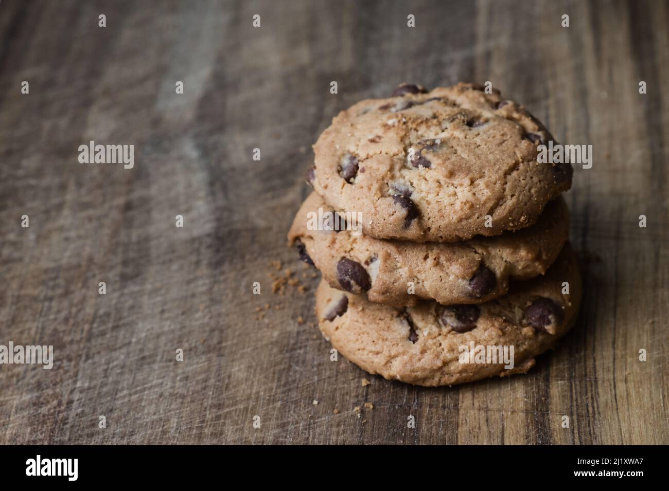 Deliziosi biscotti al cioccolato su un tavolo di legno. Tre biscotti con pezzi di cioccolato impilati su una superficie di legno. Foto Stock