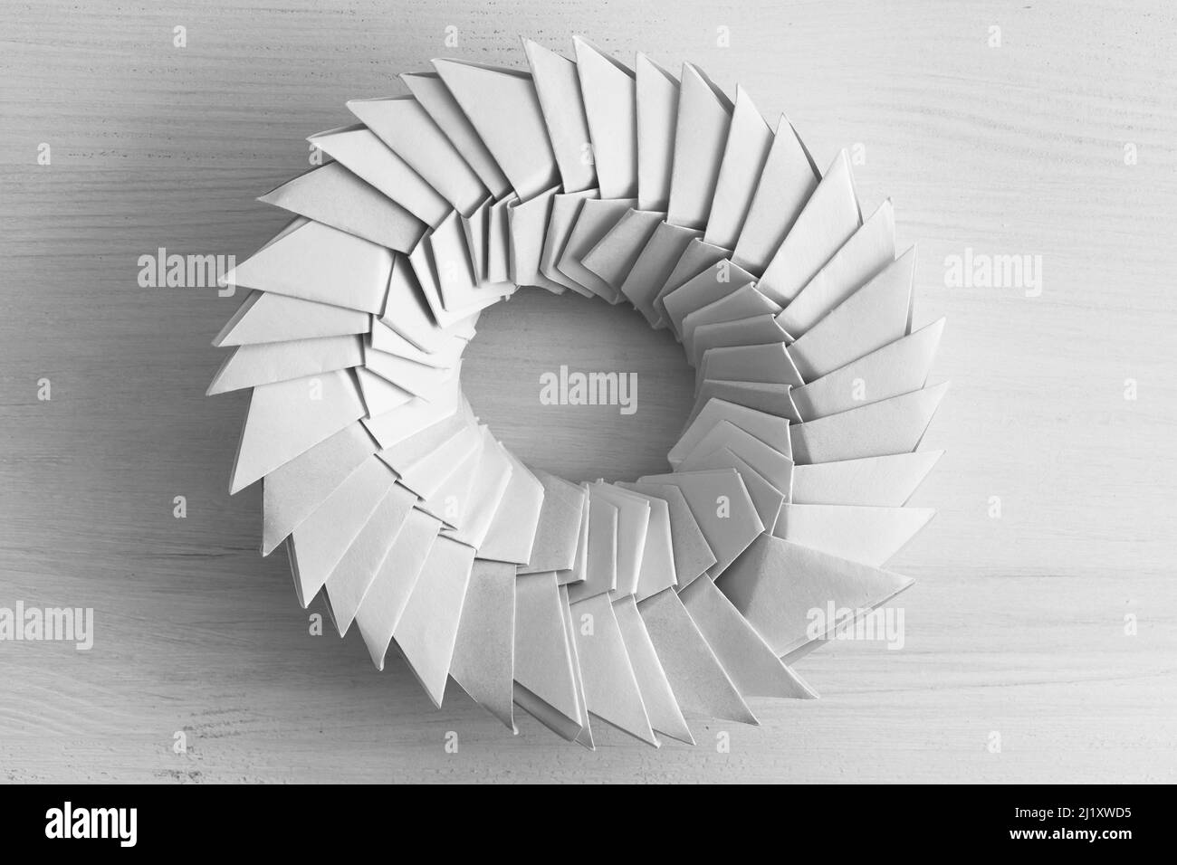 Anello Origami. L'oggetto parametrico astratto costituito da fogli di carta collegati si trova su una tabella, vista dall'alto Foto Stock