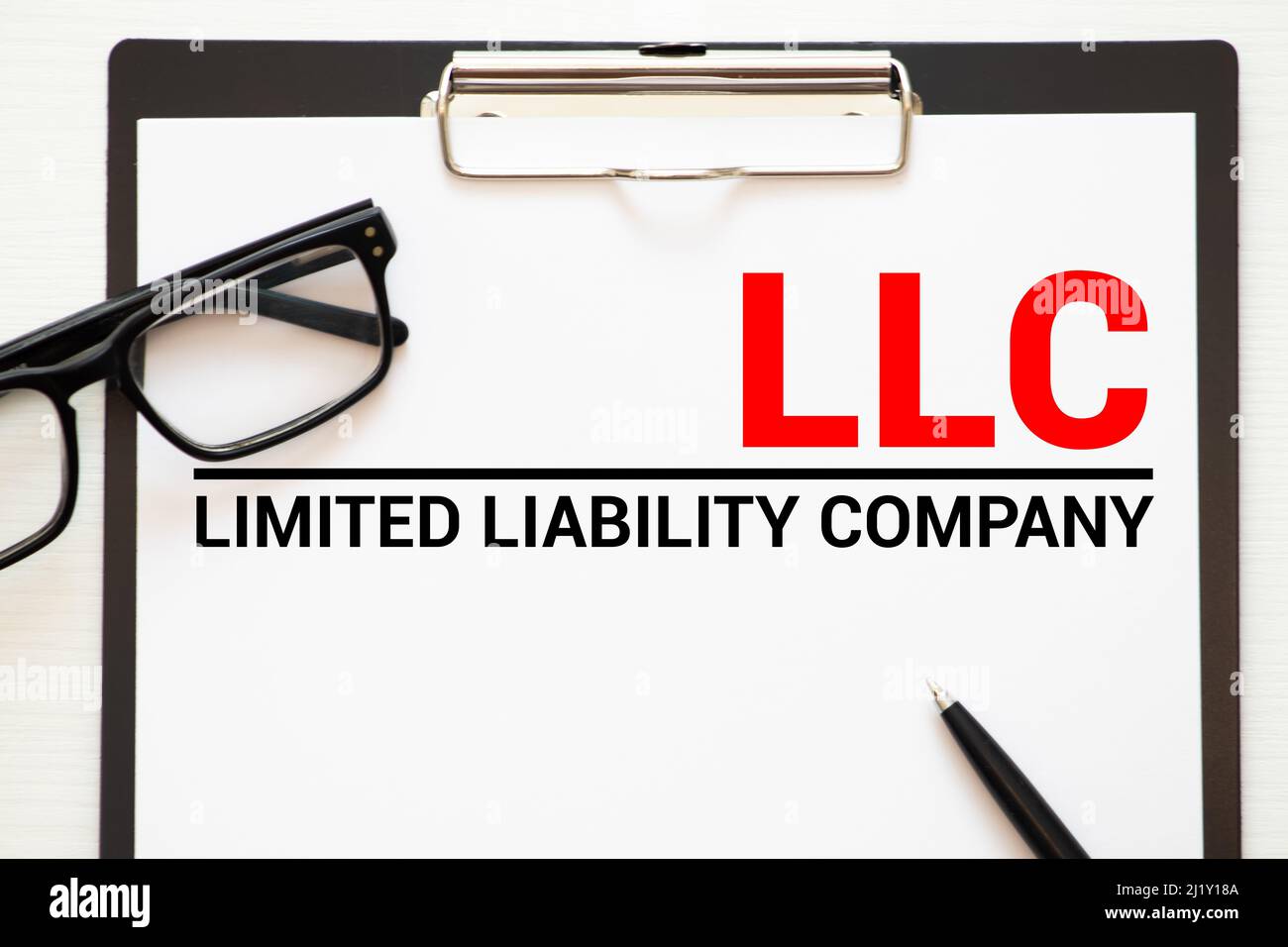 LLC Limited Liability Company - scrittura a mano su carta con tazza di caffè e penna, acronimo business concept. Foto Stock