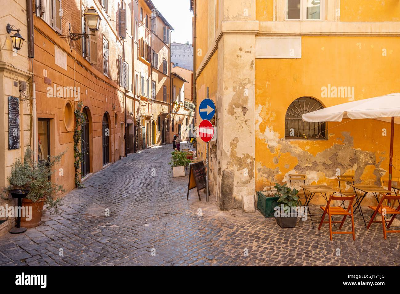 Strada stretta con caffè e piccoli negozi a Roma Foto Stock