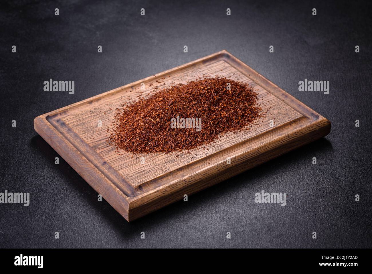 Tè Rooibos in una ciotola bianca su sfondo nero. Disposizione piatta, vista dall'alto, spazio di copia Foto Stock