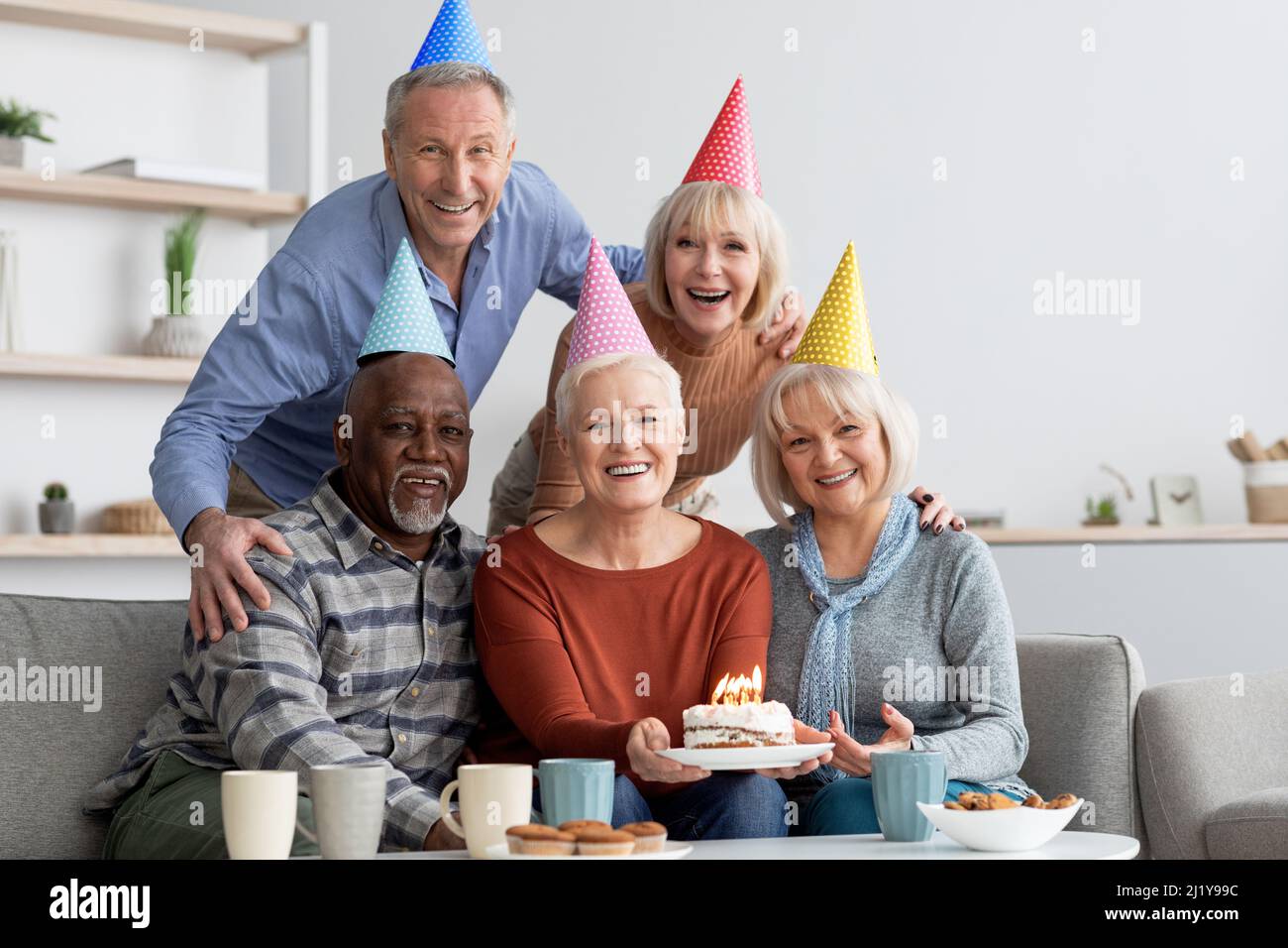 Gruppo internazionale di anziani che hanno festa di compleanno a casa Foto Stock