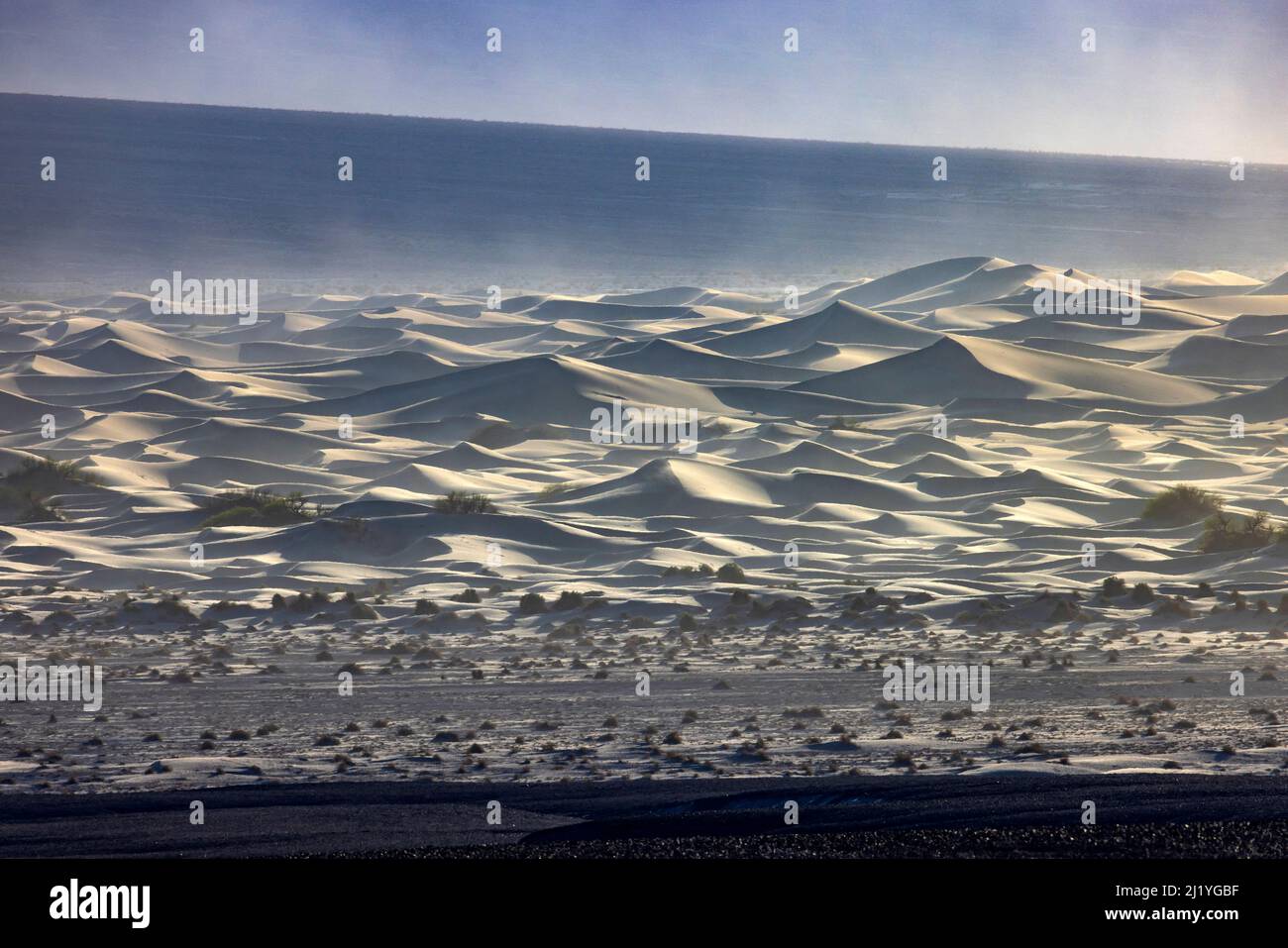 Il vento soffia la sabbia attraverso le dune sabbiose di Mesquite Flat vicino a Stovepipe Wells nel Death Valley National Park, California, USA. Foto Stock