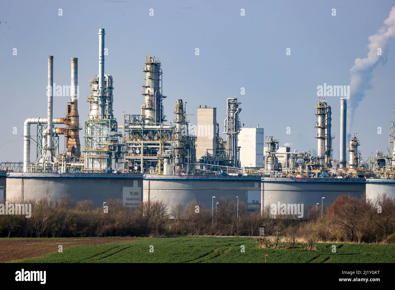 Leuna, Germania. 28th Mar 2022. Le strutture della raffineria Total si torreggiano dietro un allevamento di carri armati. Attualmente, le imprese del sito chimico di Leuna non prevedono di cessare la produzione in vista della guerra in Ucraina. Tuttavia, il gruppo Total prevede di operare in futuro senza petrolio russo. Attualmente la raffineria Leuna elabora dodici milioni di tonnellate di petrolio greggio dalla Russia all'anno per produrre combustibili come benzina e diesel, nonché prodotti chimici di base come il metanolo. Credit: Jan Woitas/dpa-Zentralbild/dpa/Alamy Live News Foto Stock