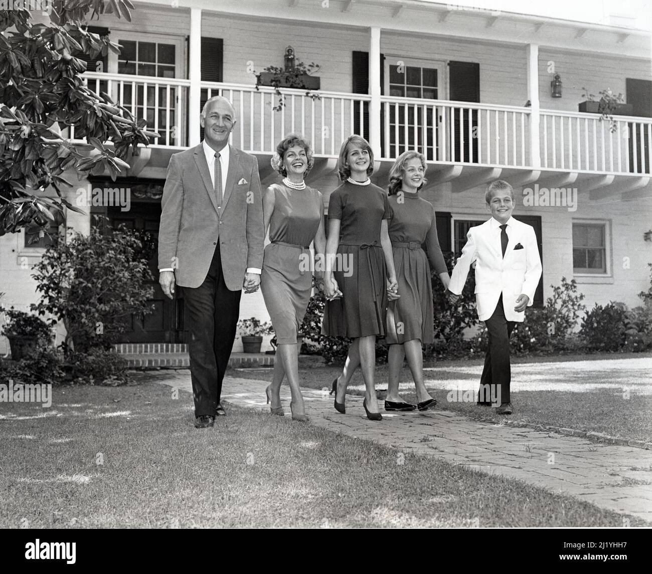 La famiglia Tom Harmon cammina di fronte alla loro casa tenendo le mani. Thomas Dudley Harmon, a volte noto con il soprannome "Old 98", il calcio americano Foto Stock