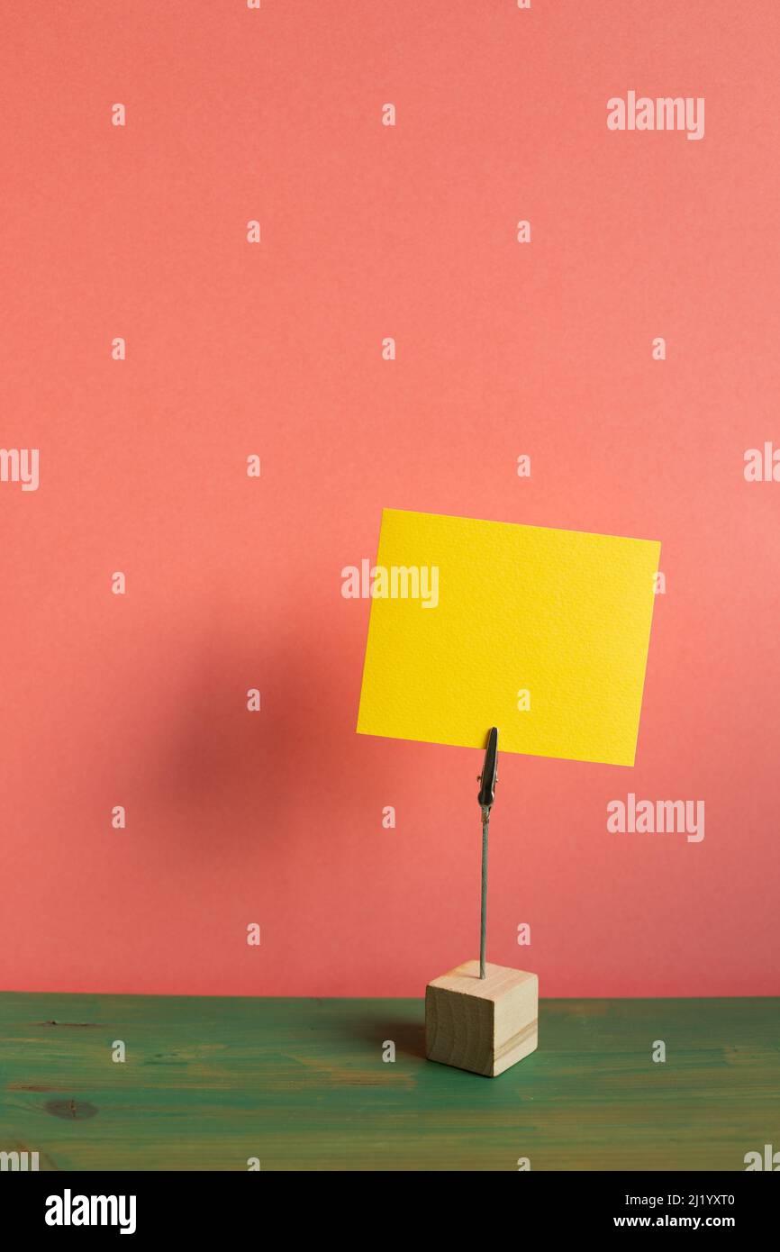 Portamalini con scheda vuota su scrivania in legno verde. Sfondo rosa parete. Spazio copia Foto Stock