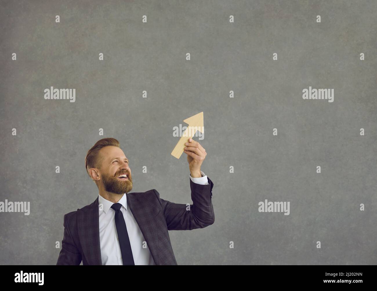 Un uomo d'affari felice che tiene la freccia che va in su come metafora per la crescita di affari ed il successo Foto Stock