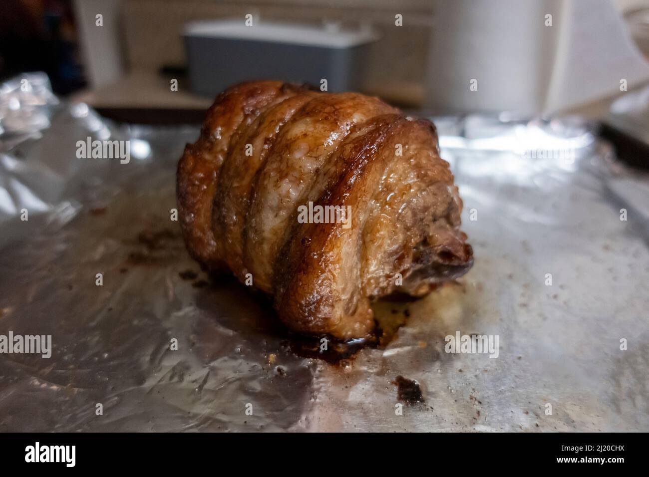 Primo piano, focalizzazione selettiva su un succoso arrosto di chashu di maiale poggiato su foglio di stagno dopo essere stato cotto Foto Stock
