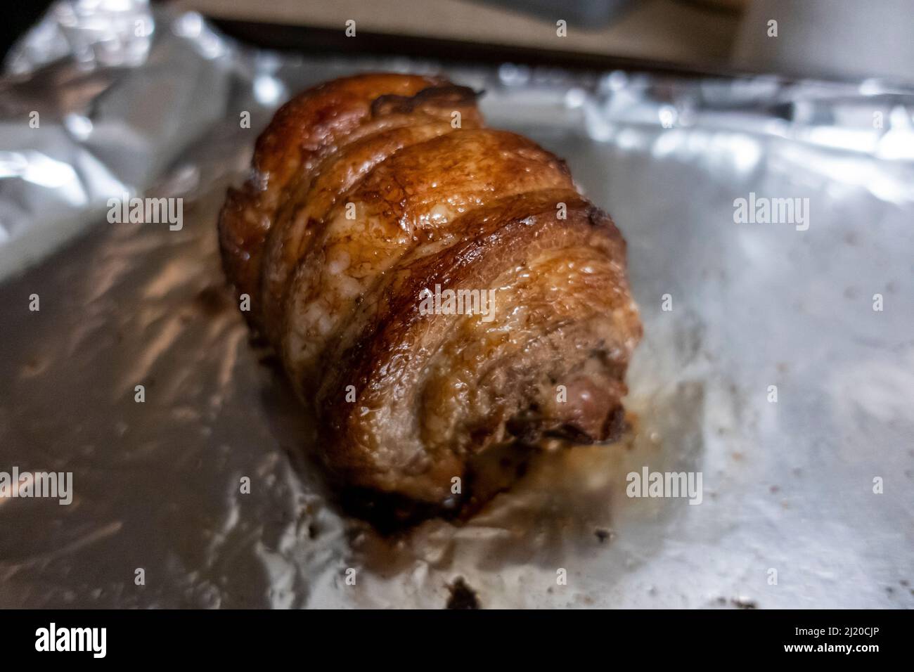 Primo piano, focalizzazione selettiva su un succoso arrosto di chashu di maiale poggiato su foglio di stagno dopo essere stato cotto Foto Stock