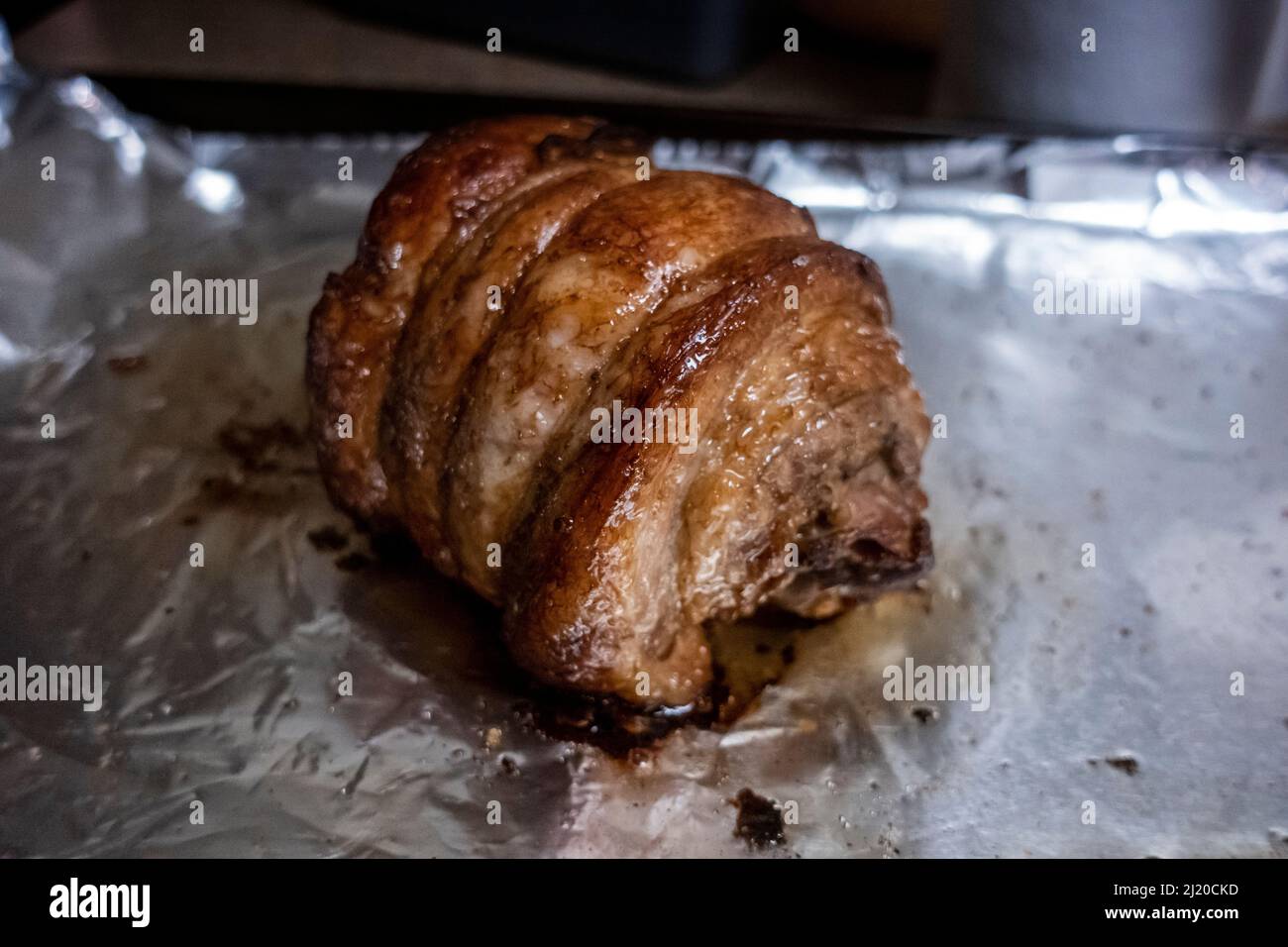 Primo piano, focalizzazione selettiva su un succoso arrosto di chashu di maiale poggiato su foglio di stagno dopo essere stato cotto Foto Stock
