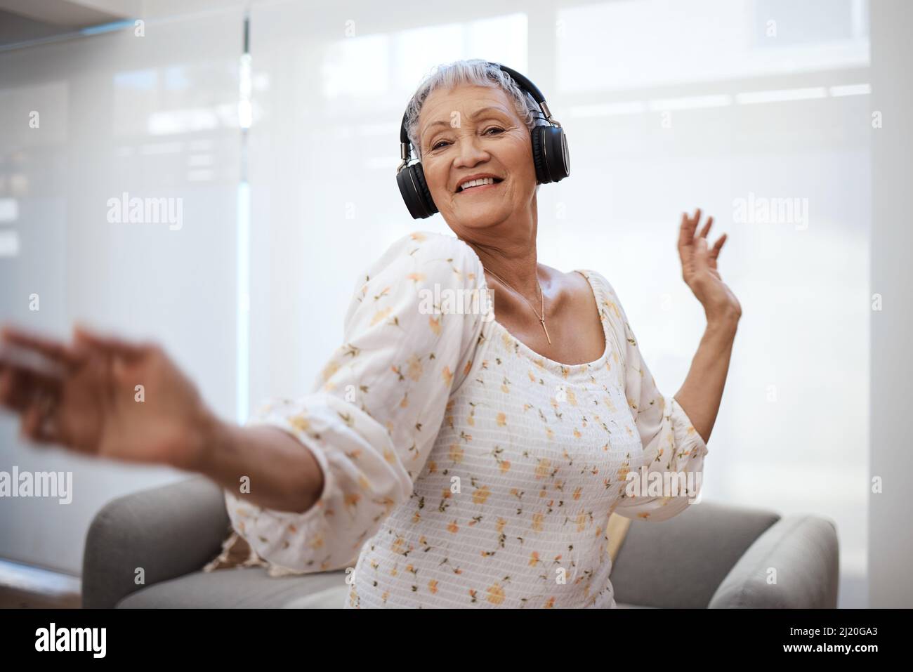 Ogni volta che danzate, sfidate la vostra età un po' di più. Scatto di una donna anziana che balla mentre usa le cuffie a casa. Foto Stock