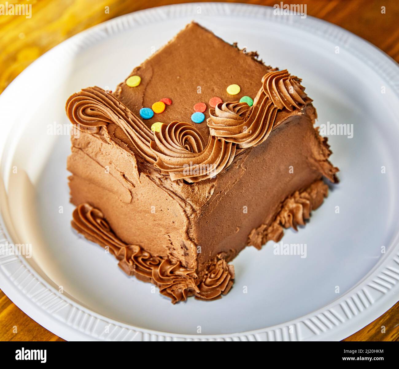 Pezzo di torta al cioccolato con decorazioni su un piatto di carta con profondità di campo poco profonda Foto Stock