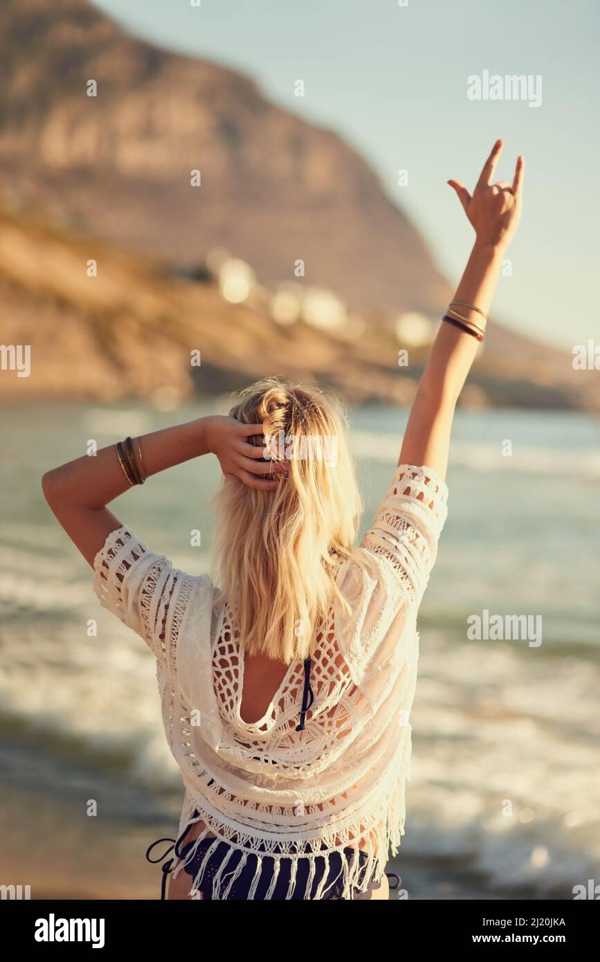 Niente è paragonabile a quella sensazione estiva. Foto di una giovane donna sulla spiaggia con la mano nell'aria. Foto Stock
