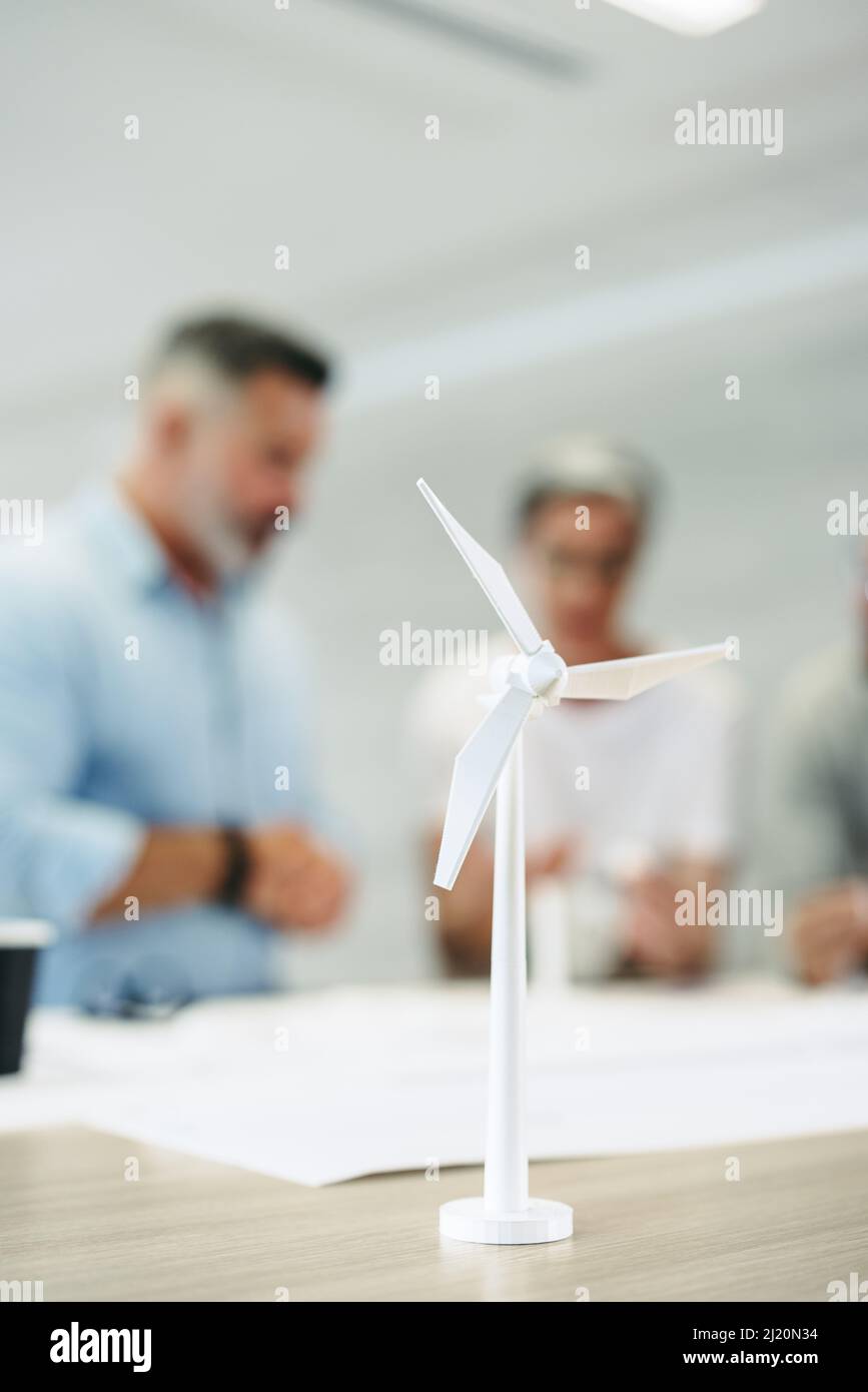 Gruppo di ingegneri creativi che lavorano con 3D modelli di turbine eoliche in un ufficio moderno. Team di uomini d'affari innovativi brainstorming mentre si lavora su un Foto Stock