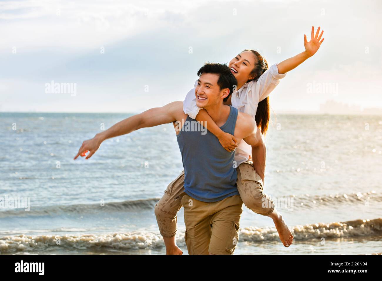 Marito che porta la moglie su una spiaggia estiva - foto di scorta Foto Stock
