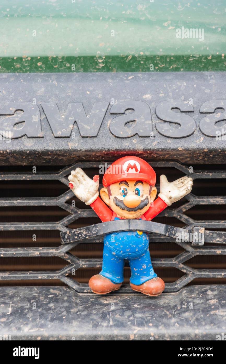 Modello supermario in plastica con le mani in posizione di consegna davanti al veicolo di servizio Kawasaki Foto Stock