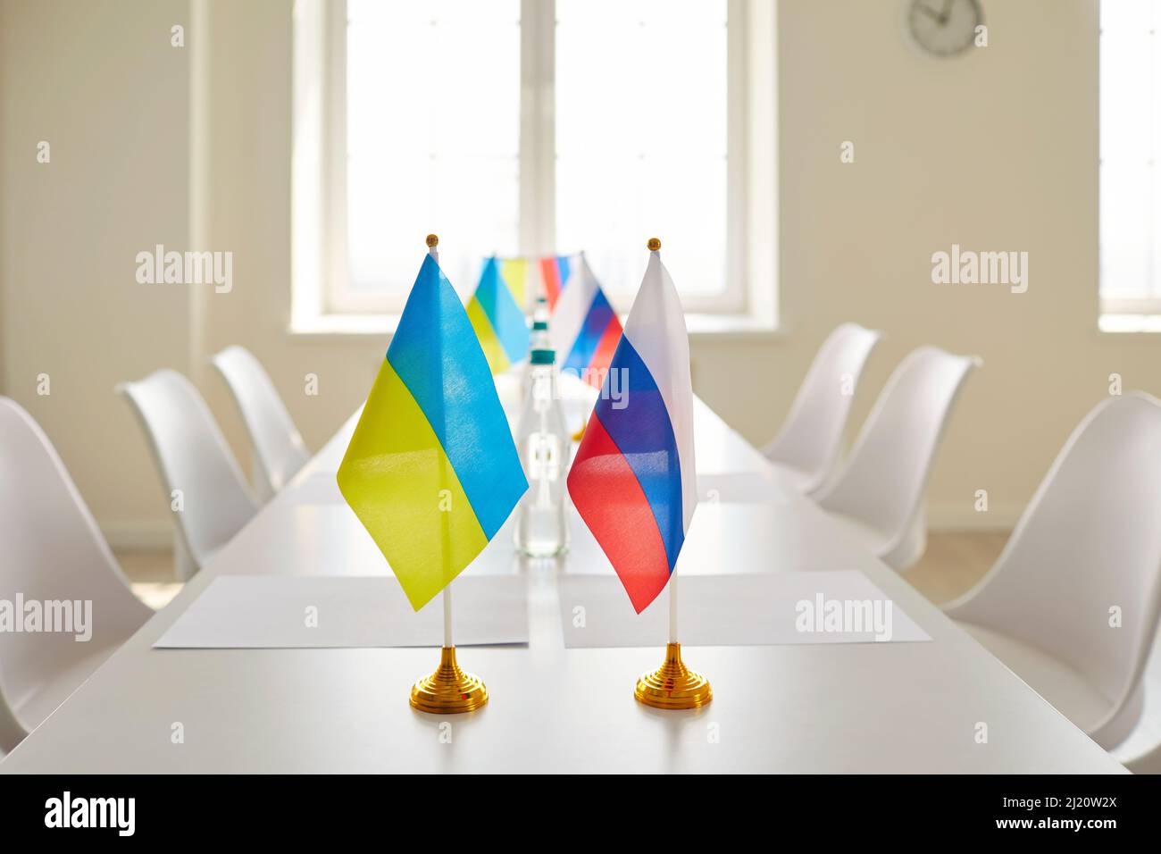 Tavolo con bandiere ucraine e russe in sala conferenze vuota prima della negoziazione Foto Stock