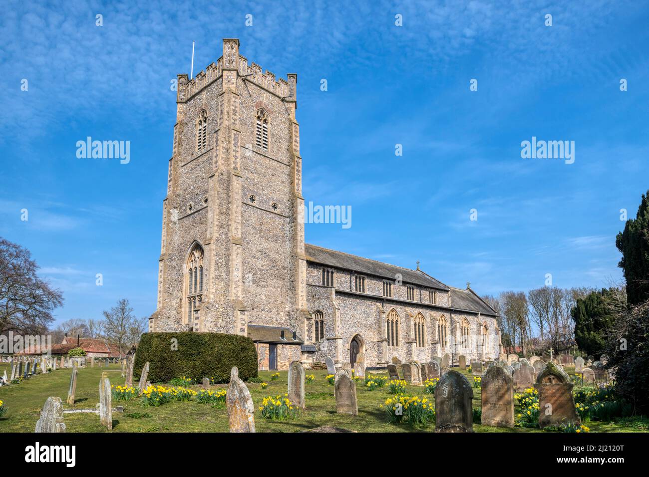 St James' Church a Castle Acre, Norfolk, con cieli blu e fiori primaverili nel cortile. Foto Stock