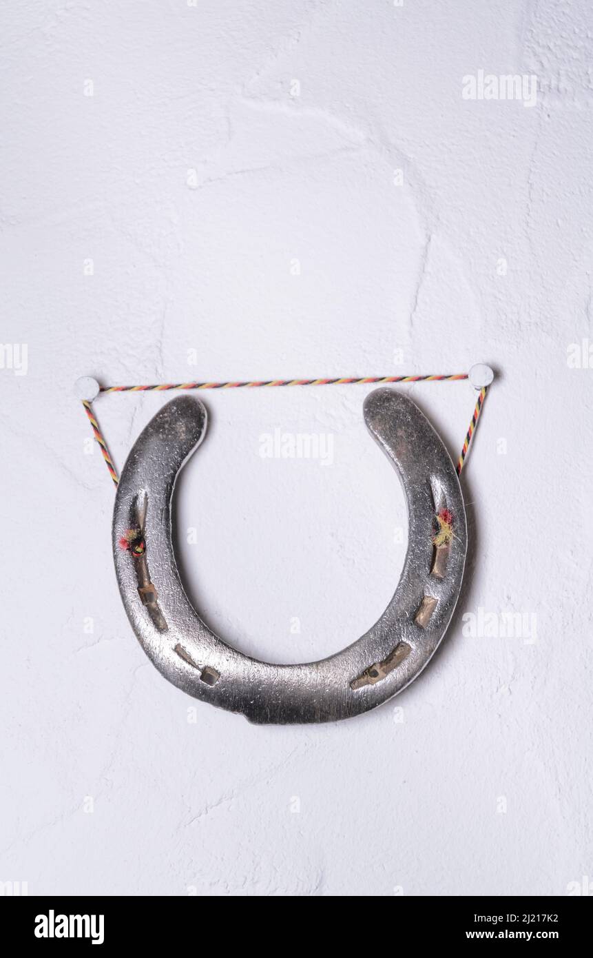 Ferro di cavallo di metallo appeso a una parete bianca come decorazione interna, concetto di fascino di buona fortuna Foto Stock
