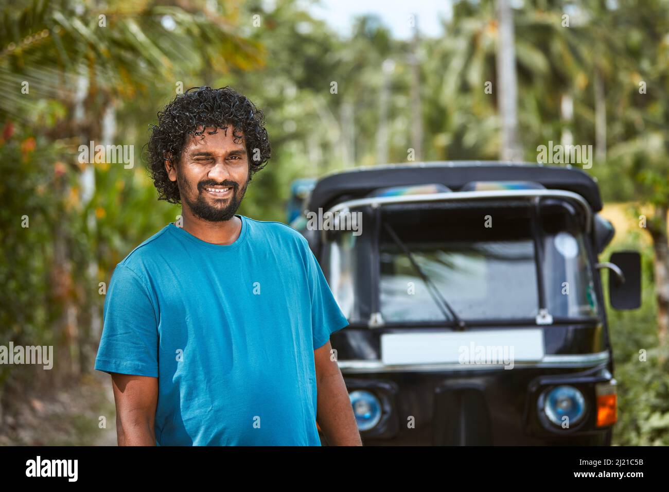 Ritratto di sorridente tuk tuk driver su strada rurale. Popolare moto a tre ruote in Sri Lanka. Foto Stock