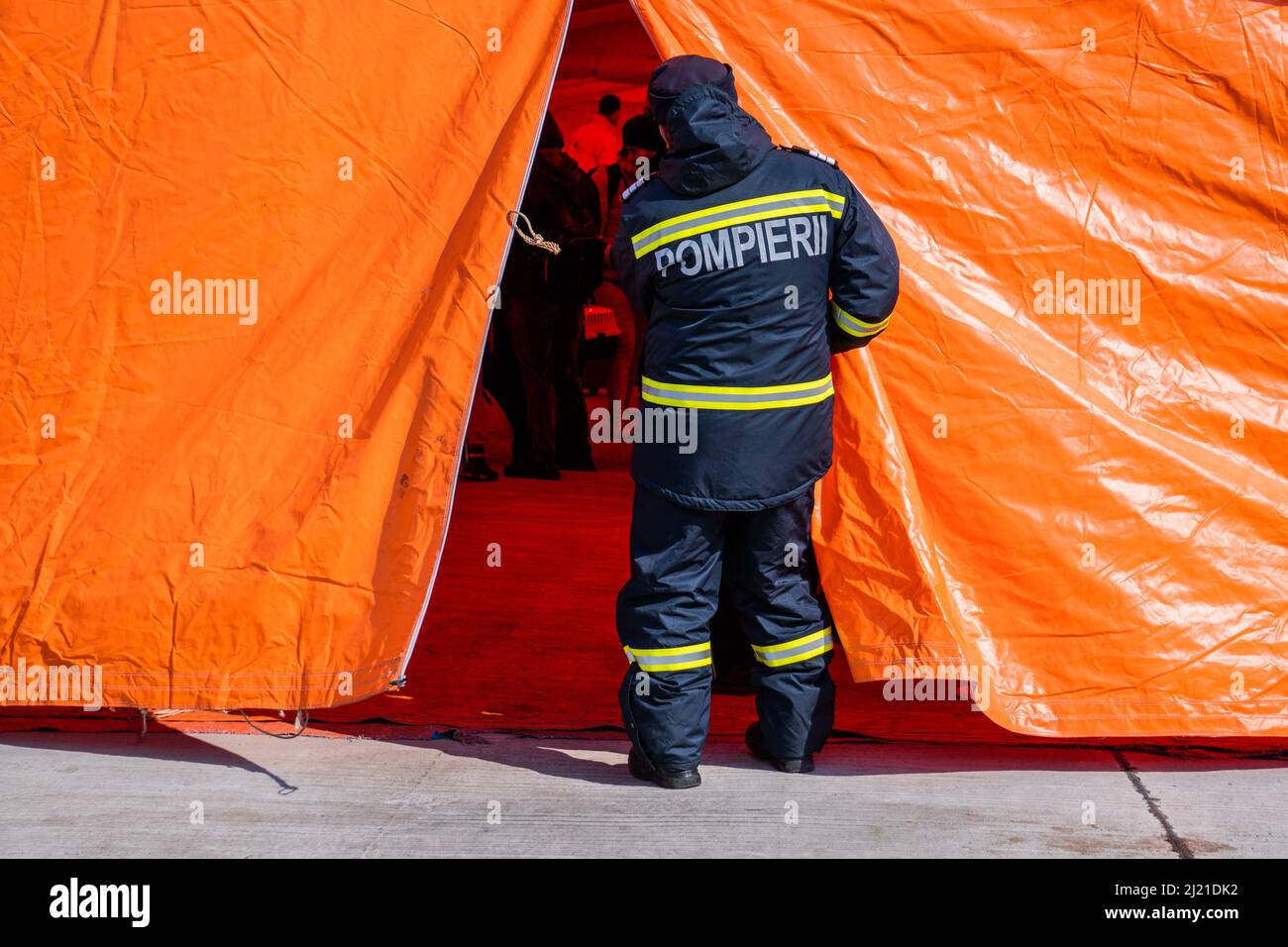 L'ufficiale dei vigili del fuoco prende uno sguardo all'interno della tenda di triage, dove i rifugiati ucraini appena arrivati aspettano di avere i loro documenti controllati. Per coloro che dispongono di passaporti biometrici sono previste linee diverse. I volontari portano i rifugiati in attesa all'interno di bevande calde e coperte. Foto di anca Gheonea/ABACAPRESS.COM Foto Stock