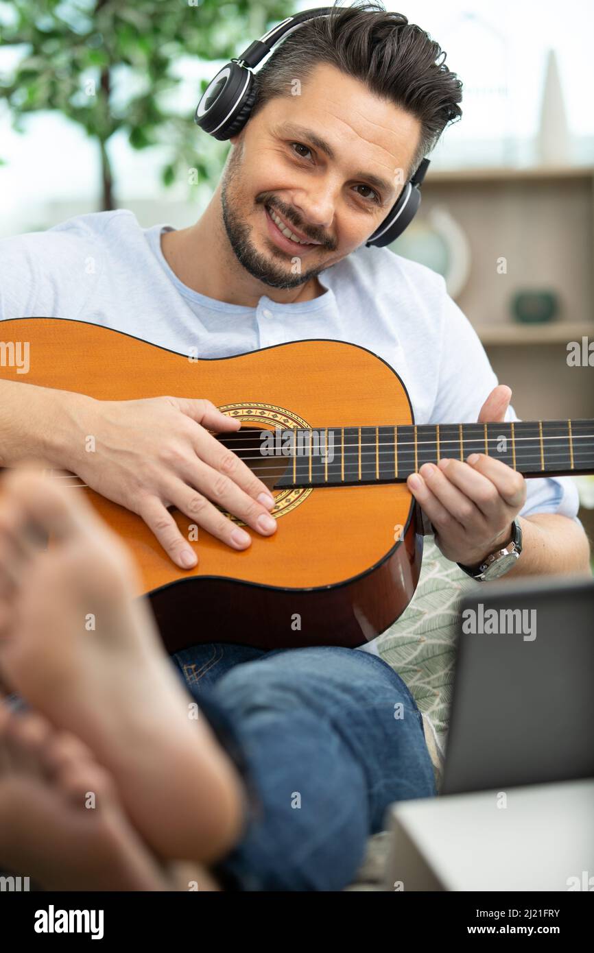 guy in cuffie sta suonando la chitarra utilizzando un computer portatile  Foto stock - Alamy