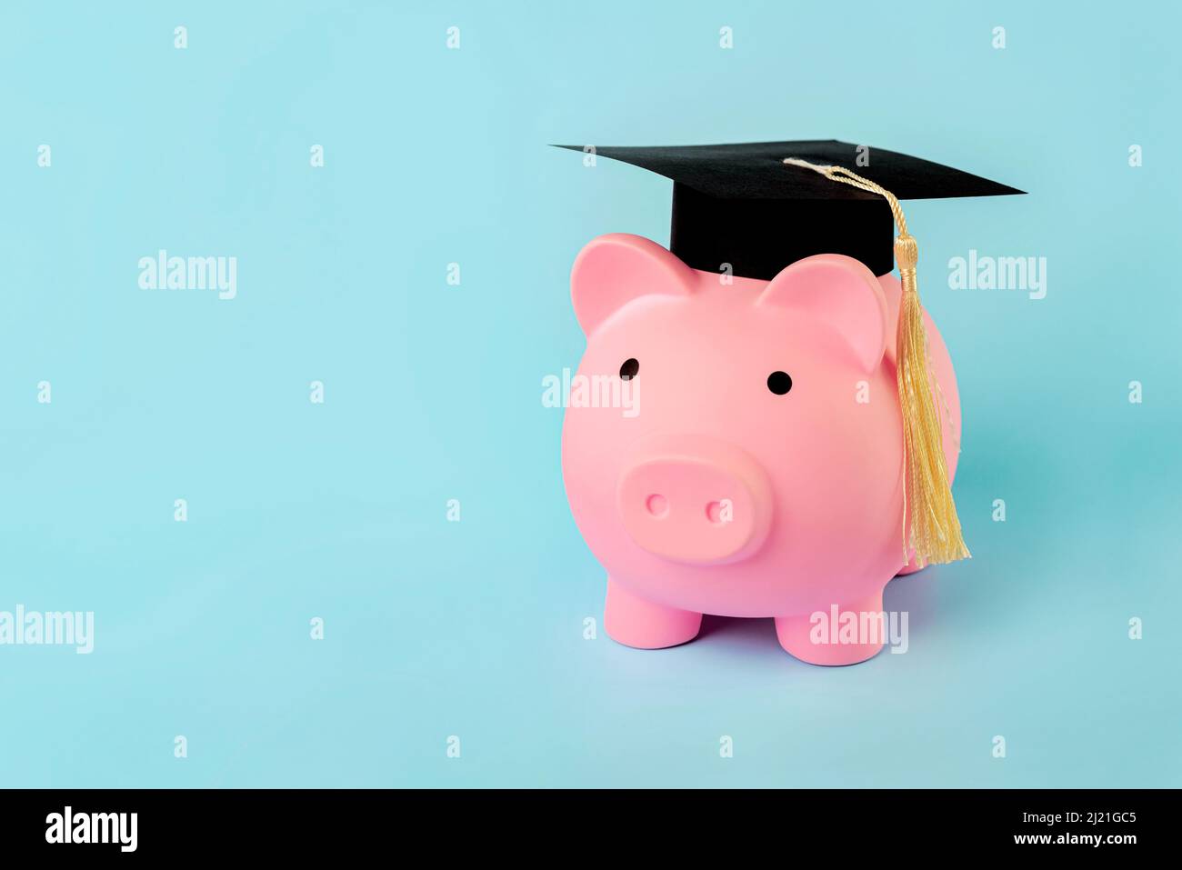 Banca di denaro rosa a forma di maialino con tappo graduato e spazio di copia su sfondo blu Foto Stock