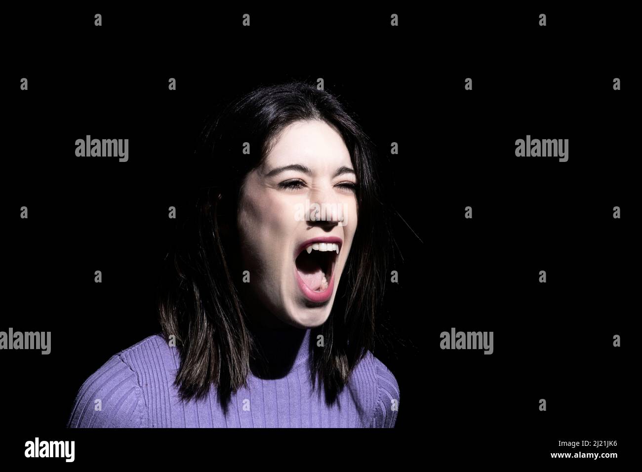 vampiro donna su sfondo nero urlando Foto Stock