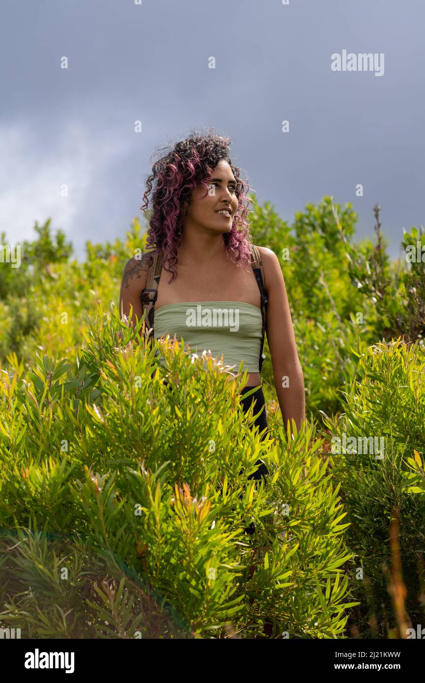 Donna in piedi tra piante fogliame in natura Foto Stock