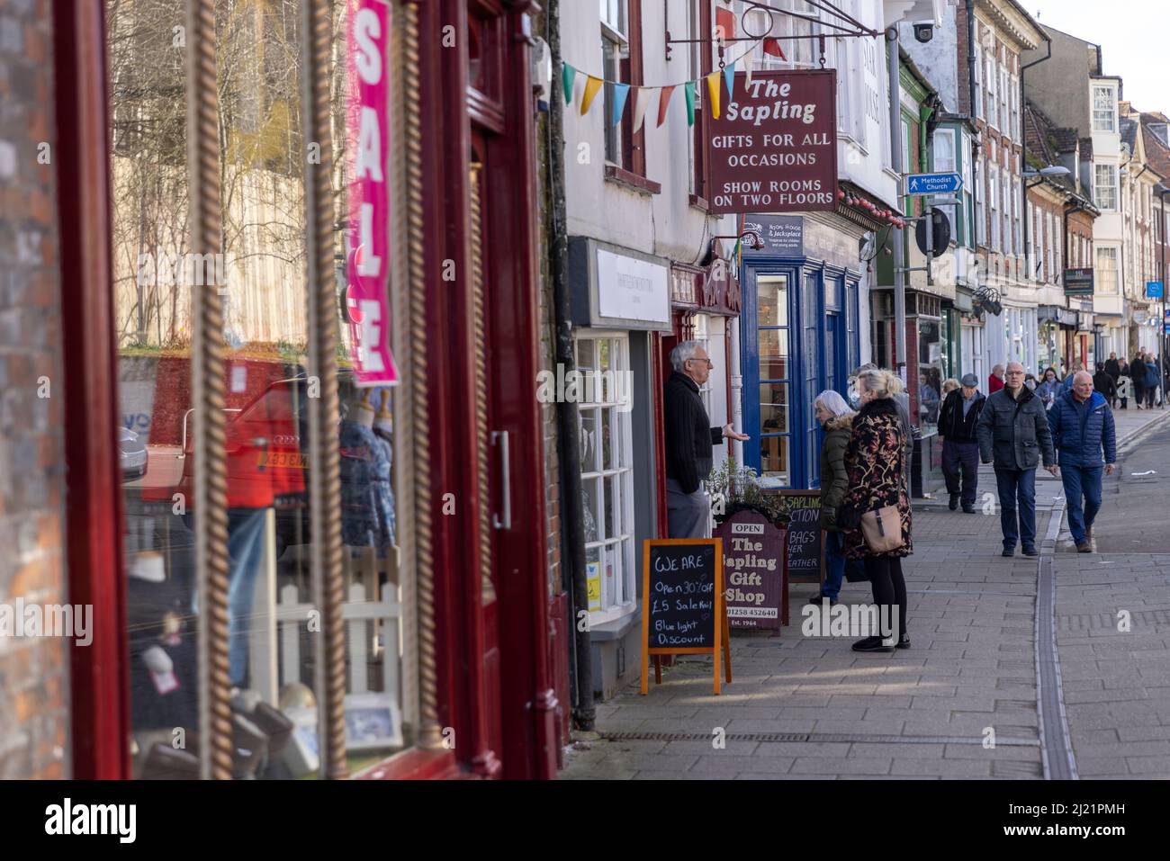 Un negoziante che ha una chiacchierata con una signora locale sulla strada principale, Blandford Forum, Dorset, Inghilterra, Regno Unito Foto Stock