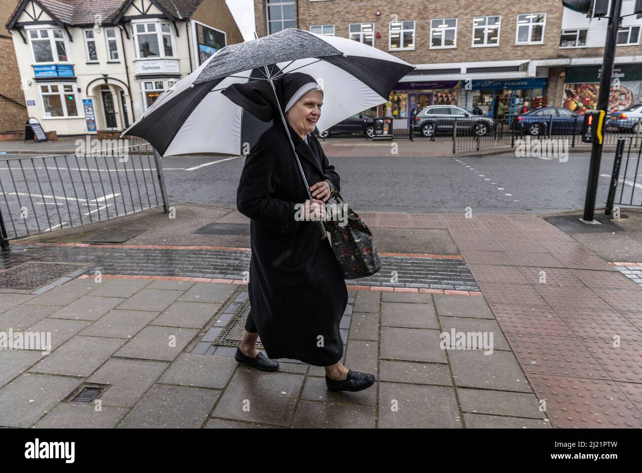 Catholic Nun on the Run between rain showers, a Bushey, Hertfordshire, Inghilterra, Regno Unito Foto Stock