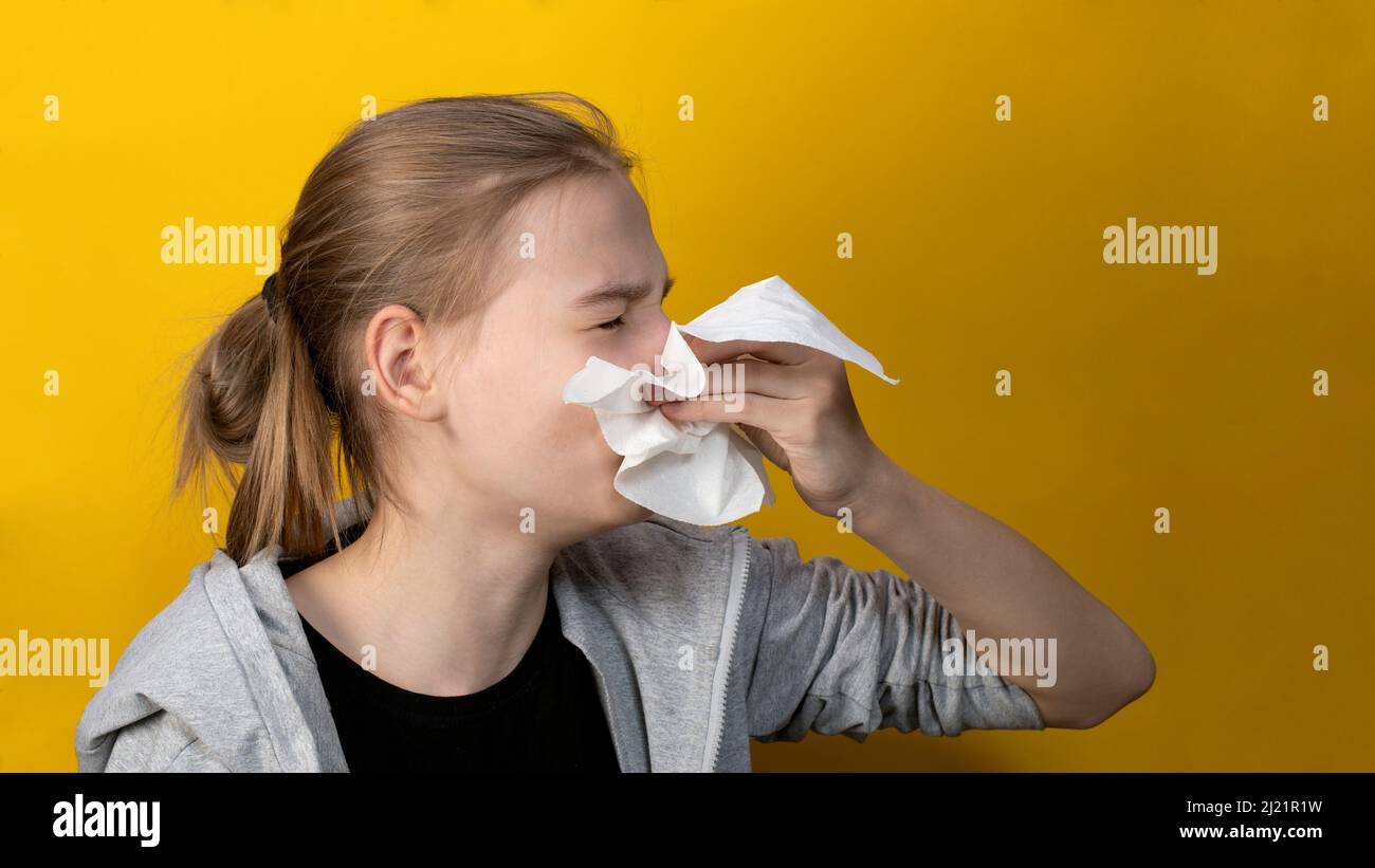 Giovane donna malata che tiene il fazzoletto di tessuto che soffia il naso. Concetto di raffreddore e influenza Foto Stock
