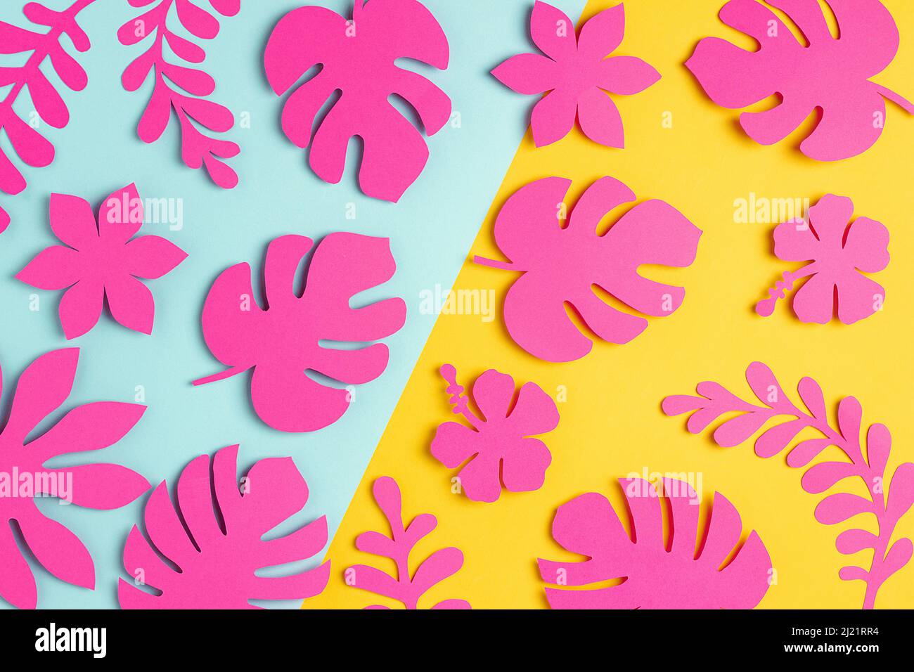 Trendy luce solare motivo tropicale fatto con fiori di carta rosa brillante e foglie su sfondo giallo blu, come sfondo o struttura. Conc. Floreale minimale Foto Stock