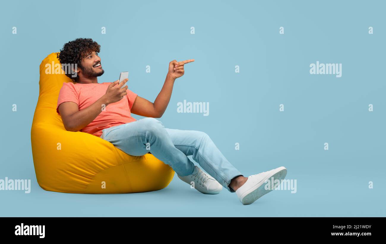 Uomo indiano felice con smartphone che punta allo spazio di copia Foto Stock